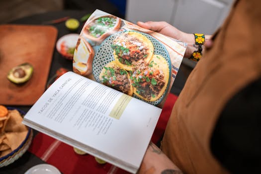 pexels-photo-5737454-5737454 A person holding a cookbook open to a delicious tacos recipe.