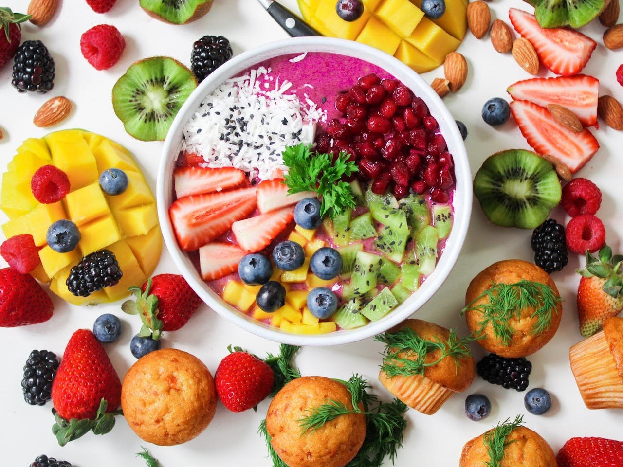 contact-img Vibrant smoothie bowl topped with assorted fresh fruits and muffins, perfect for a healthy snack.