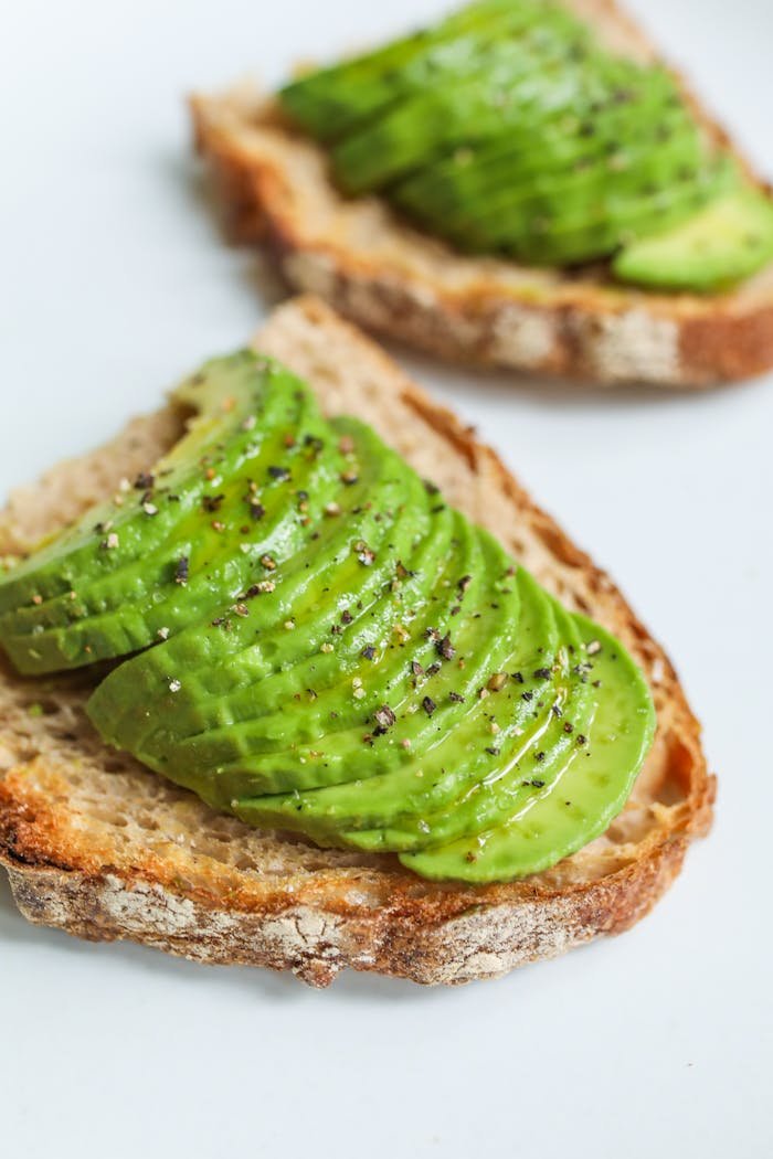 Sliced avocado atop sourdough bread, seasoned with pepper, photographed for a food photography series.
